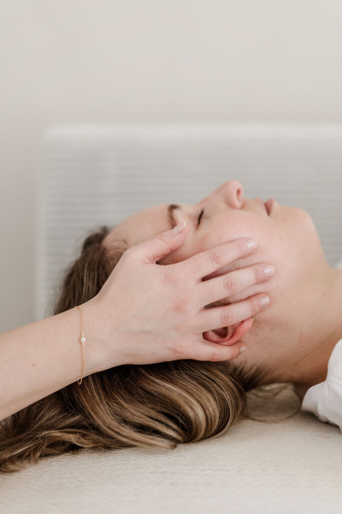 Nahaufnahme - Johanna Habel legt während einer Craniosacral Therapie ihre Hände an die Schläfen einer Patientin