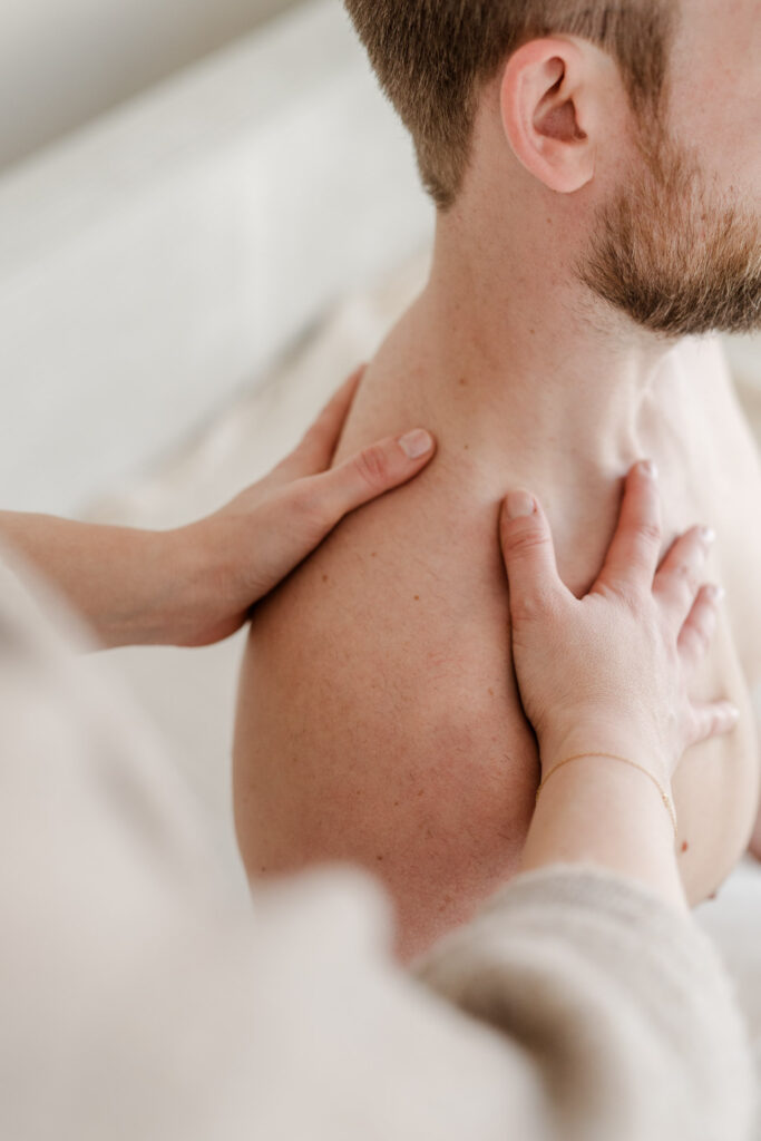 Komplementärtherapeutin Johanna Habel legt ihre Hände auf den nackten Oberkörper eines Mannes während einer Craniosacral Behandlung